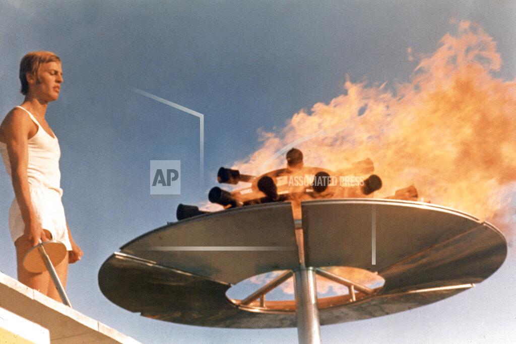 Uncredited Runner Guenther Zahn stands near the Olympic flame he lit above the Olympic Stadium on Aug. 26, 1972, during the opening ceremony of the Summer Olympic Games in Munich, Germany. (AP Photo)