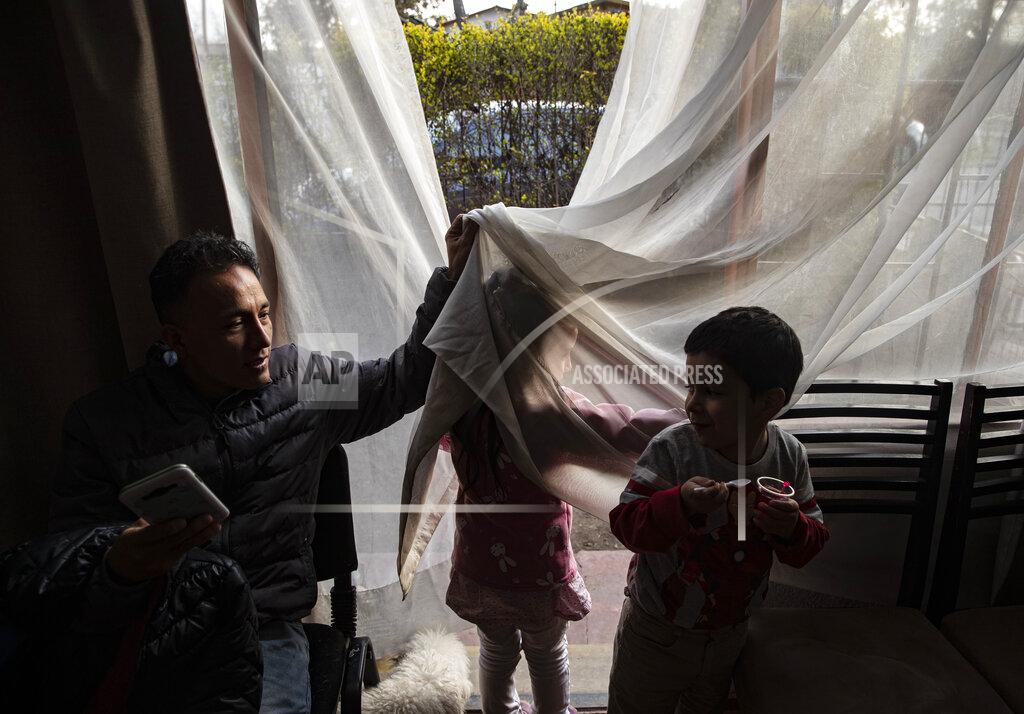 Esteban Felix Jose Collantes lifts a curtain to encourage his five-year-old daughter Kehity to return from the patio, where she wanted to be alone, and rejoin a birthday party at a friends' home in Santiago, Chile, Sunday, Aug. 23, 2020, two months after her mother, his wife Silvia Cano, died of COVID-19. Collantes says his daughter hasn't cried since her mother died. (AP Photo/Esteban Felix)