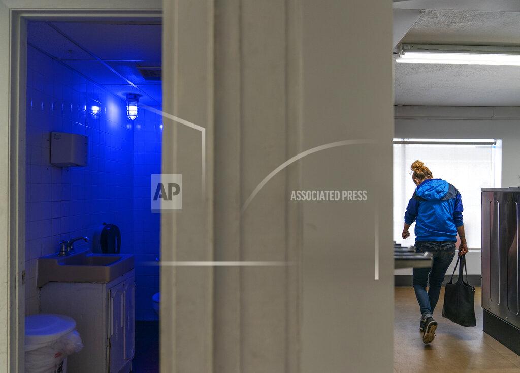 David Goldman A blue light illuminates the bathroom in the Cookie Carnival laundromat to make it harder for drug users to find a vein in Huntington, W.Va, Thursday, March 18, 2021. The laundromat was among several local businesses to install blue lights at the height of the city's opioid crisis, when they would often find syringes left behind by drug users. "It was the only thing we could think of to do to help," said manager Misti Mann-France. "And it has helped tremendously." She said people have overdosed several times in the parking lot of their business. "I wish there was a solution to the bigger problem," she said. "There are so many out there on drugs, and it's sad, it really is." (AP Photo/David Goldman)