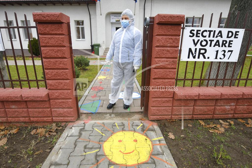 Andreea Alexandru An election official wearing a protective outfit against the COVID-19 infection waits before taking a mobile ballot box to people with mobility issues or quarantined in the village of Branesti, Romania, Sunday, Dec. 6, 2020. Voting started in Romania's legislative election expected to restore some measure of stability after five years of political and social turbulence with more than 18 million Romanians registered to vote for a new legislative body. (AP Photo/Andreea Alexandru)