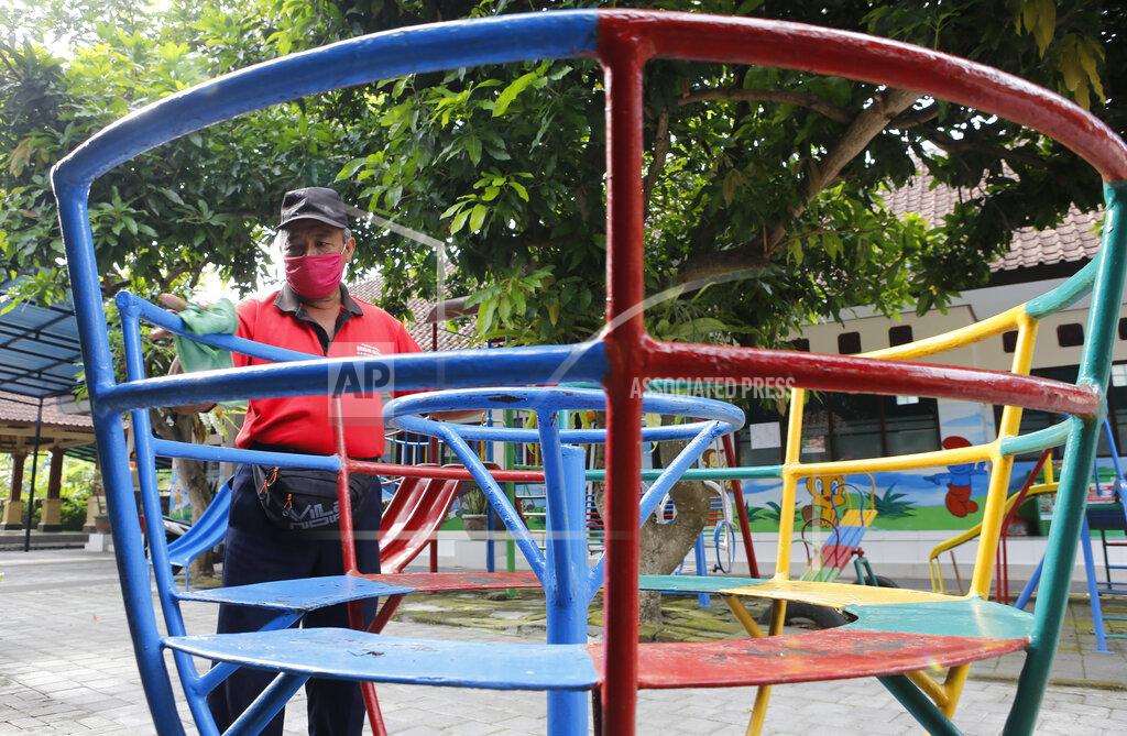 A worker wears a face mask for curbing the spread of coronavirus outbreak at an empty school ground in Bali, Indonesia on Monday, Nov. 23, 2020. (AP Photo/Firdia Lisnawati)