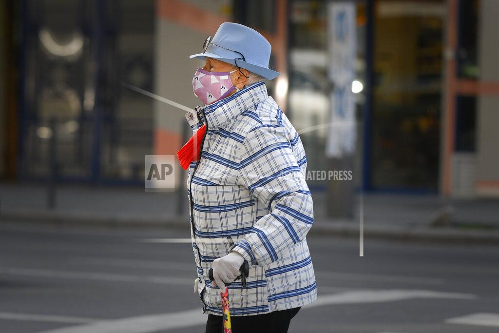 Andreea Alexandru A woman wears a face mask for protection against COVID-19 infection while crossing a street in Bucharest, Tuesday, Oct. 20, 2020. Local authorities imposed the use of face masks in all public spaces, indoors and outdoors, closed schools, restaurants, theatres and cinemas after the rate of COVID-19 infections went above 3 cases per 1000 inhabitants in the Romanian capital Bucharest. (AP Photo/Andreea Alexandru)