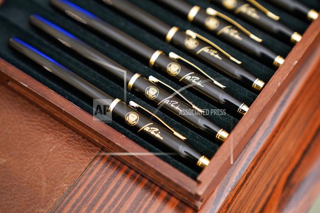 Alex Brandon FILE - In this Jan. 21, 2021, file photo pens featuring President Joe Biden's signature and presidential seal, are displayed in the State Dinning Room of the White House in Washington. (AP Photo/Alex Brandon, File)