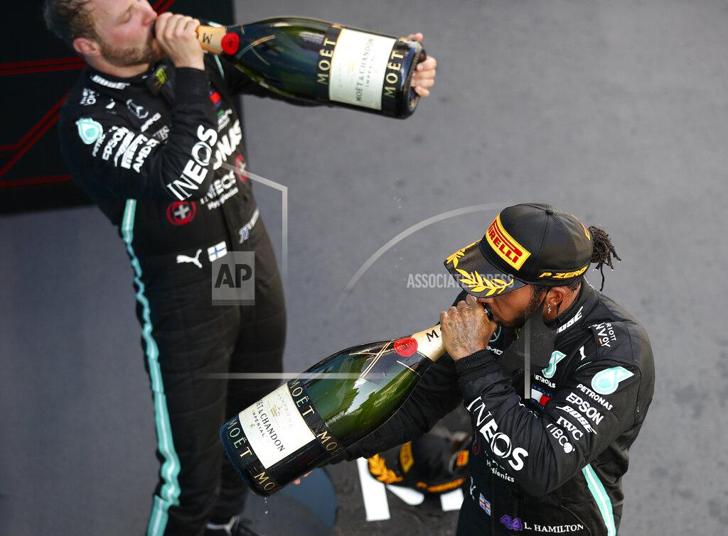 Bryn Lennon Race winner, Mercedes driver Lewis Hamilton of Britain, front, drinks champagne with third placed Mercedes driver Valtteri Bottas of Finland after the Formula One Grand Prix at the Barcelona Catalunya racetrack in Montmelo, Spain, Sunday, Aug. 16, 2020. (Bryn Lennon, Pool via AP)