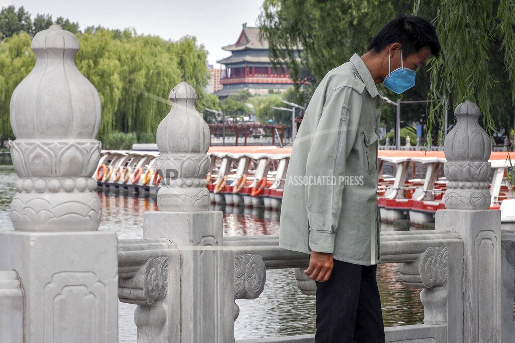 Andy Wong A man wearing a protective face mask to help curb the spread of the coronavirus stands against a roll of boats parked on the barricaded Houhai Lake, a usually popular tourist spot before the new coronavirus outbreak in Beijing, Tuesday, June 30, 2020. China, where the coronavirus pandemic began in December, was the first economy to reopen in March after the ruling Communist Party declared victory over the disease. Manufacturing and other activity is reviving but demand for exports is feeble and Chinese consumers, worried about losing jobs, are reluctant to spend. (AP Photo/Andy Wong)