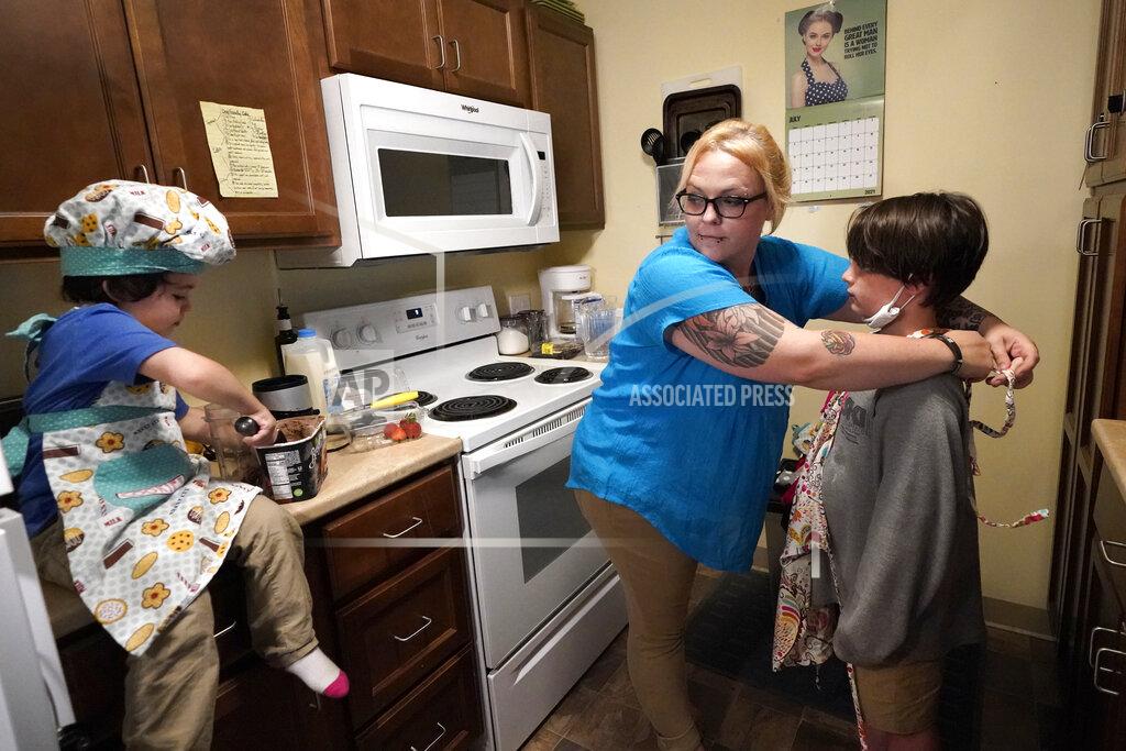 Elise Amendola In this July 28, 2021 photo, Christina Darling and her sons, Brennan, 4, left, and Kayden, 10, prepare a snack at home in Nashua, N.H. Darling and her family have qualified for the expanded child tax credit, part of President Joe Biden's $1.9 trillion coronavirus relief package. "Every step closer we get to a livable wage is beneficial. That is money that gets turned around and spent on the betterment of my kids and myself," said Darling, a housing resource coordinator who had been supplementing her $35,000-a-year salary with monthly visits to the Nashua Soup Kitchen and Shelter's food pantry. (AP Photo/Elise Amendola)