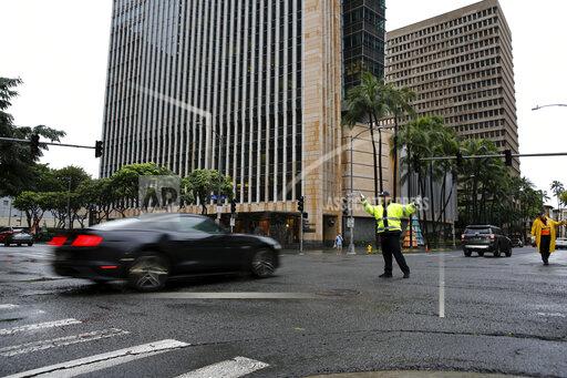 A police officer directs traffic during a power outage in downtown Honolulu after a severe winter storm swept the islands, Tuesday, Dec. 7, 2021. (AP Photo/Caleb Jones)