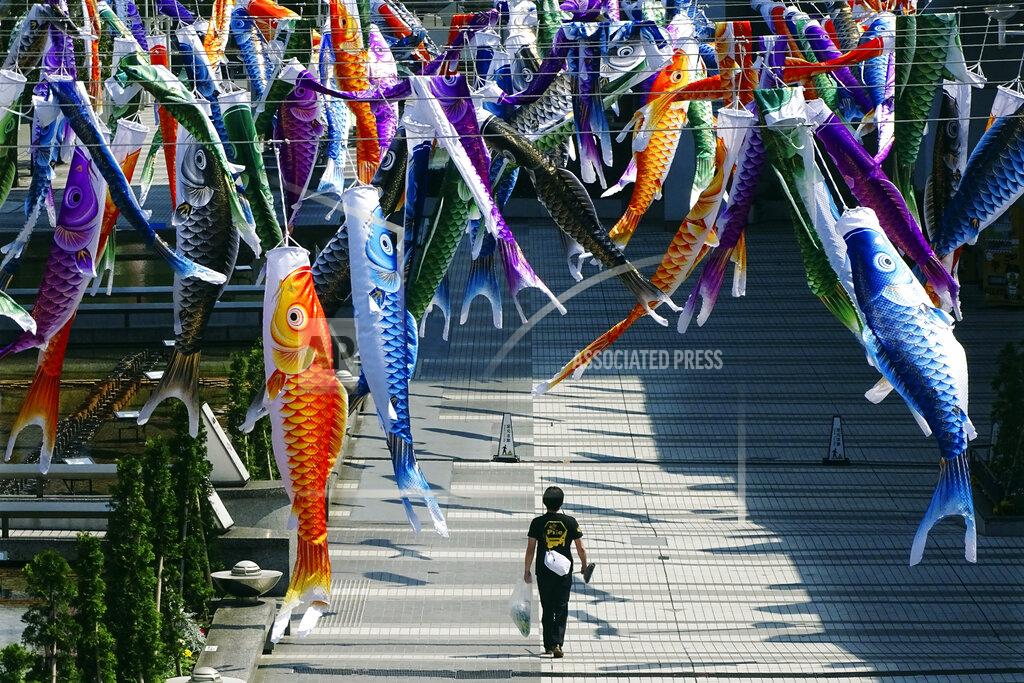 Eugene Hoshiko A man walks under the colorful carp streamers fluttering in the air in Tokyo Saturday, May 2, 2020. Prime Minister Shinzo Abe said that he planned to extend a state of emergency beyond the scheduled end of May 6 because infections are spreading and hospitals are overburdened. The streamers were hung to mark Children's Day on May 5, wishing children's healthy growth like carp that can swim up a waterfall. (AP Photo/Eugene Hoshiko)