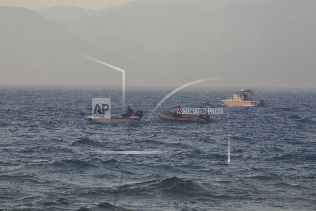 Andreas Alexopoulos Firefighters and volunteers in vessels stand by the beach during a wildfire near Lampiri village, west of Patras, Greece, Saturday, Jul. 31, 2021. The fire, which started high up on a mountain slope, has moved dangerously close to seaside towns and the Fire Service has send a boat to help in a possible evacuation of people. (AP Photo/Andreas Alexopoulos)