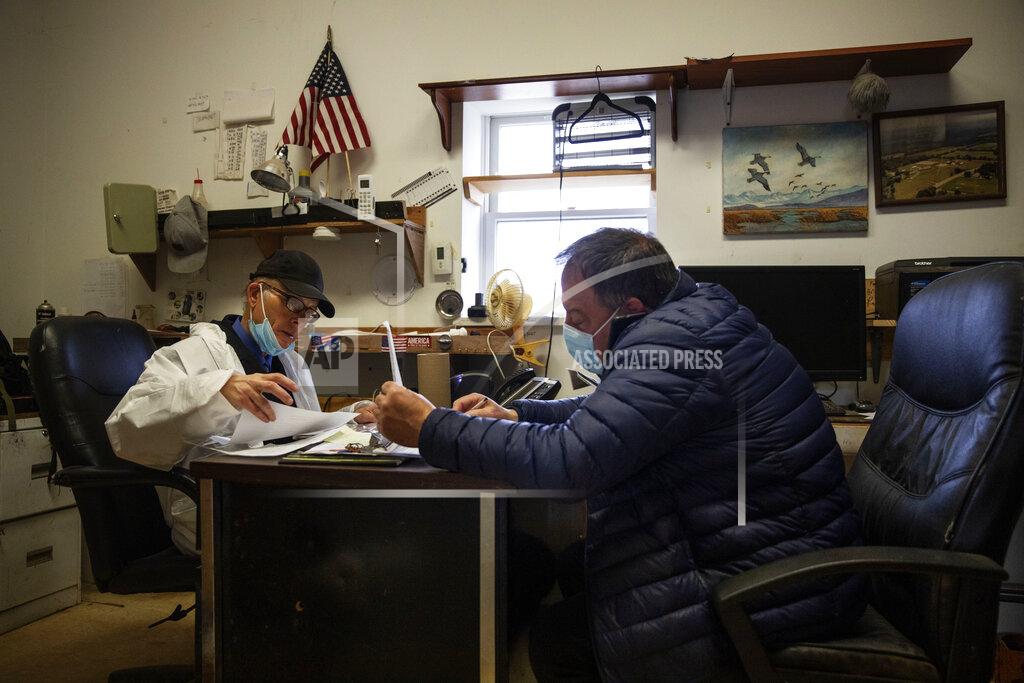 David Goldman Rabbi Shmuel Plafker, left, and funeral director James Donofrio work in the office of Hebrew Free Burial Association's cemetery as they deal with a surge in burials, mostly of those who died from coronavirus, in the Staten Island borough of New York, Tuesday, April 7, 2020. Staffers find themselves exchanging texts about death certificates at 2 a.m. and fielding dozens of calls at a time. It takes its toll on everyone. (AP Photo/David Goldman)