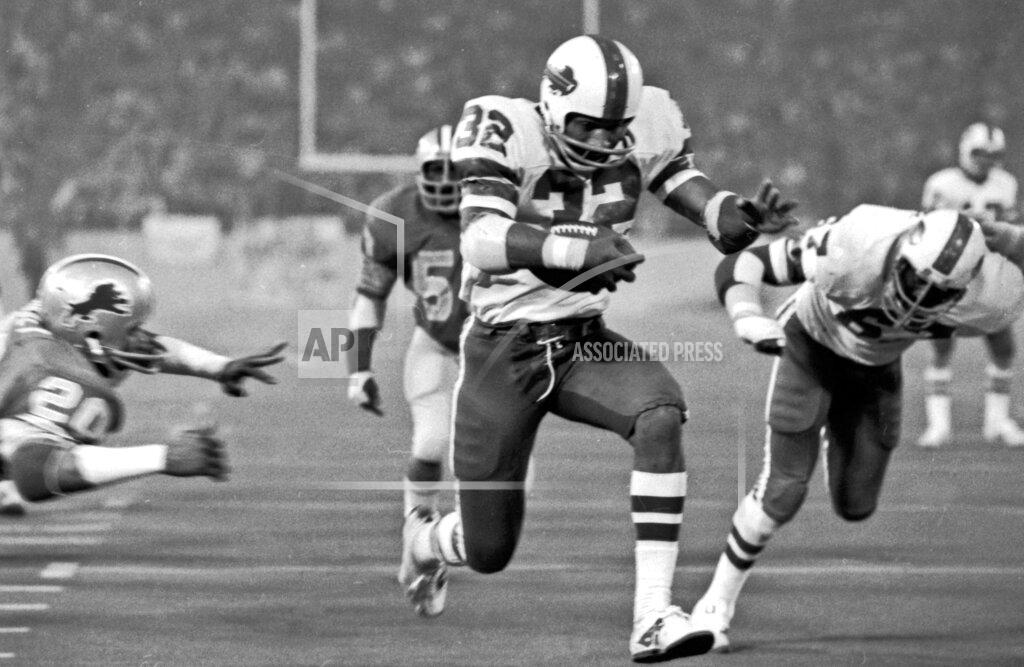 Uncredited FILE - In this Nov. 25, 1976, file photo, Buffalo Bills' O.J. Simpson rushes through a large hole in the center ofthe Detroit Lions defensive line to score on a 12-yard run for his second touchdown in the NFL football game in Pontiac, Mich. The former Heisman Trophy winner from Southern Cal became the first player in NFL history to run for more than 2,000 yards in a season in 1973, finishing with 2,003 yards. (AP Photo/File)