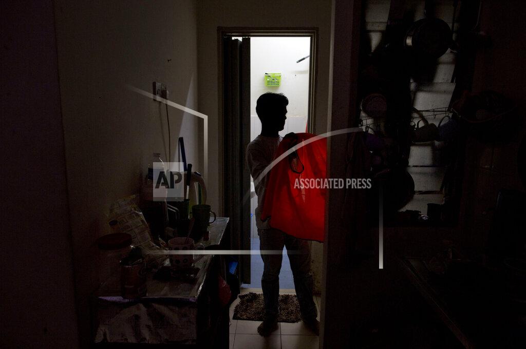 Gemunu Amarasinghe Shamshu, a member of Myanmar's long-persecuted Rohingya minority, changes clothes upon returning home in peninsular Malaysia, Monday, March 4, 2019. Shamshu is part of an invisible workforce made up of millions of poor laborers, including many who face exploitation and abuse, within Malaysia and neighboring Indonesia. Together, the two countries produce an estimated 85 percent of the world's $65 billion palm oil supply. (AP Photo/Gemunu Amarasinghe)