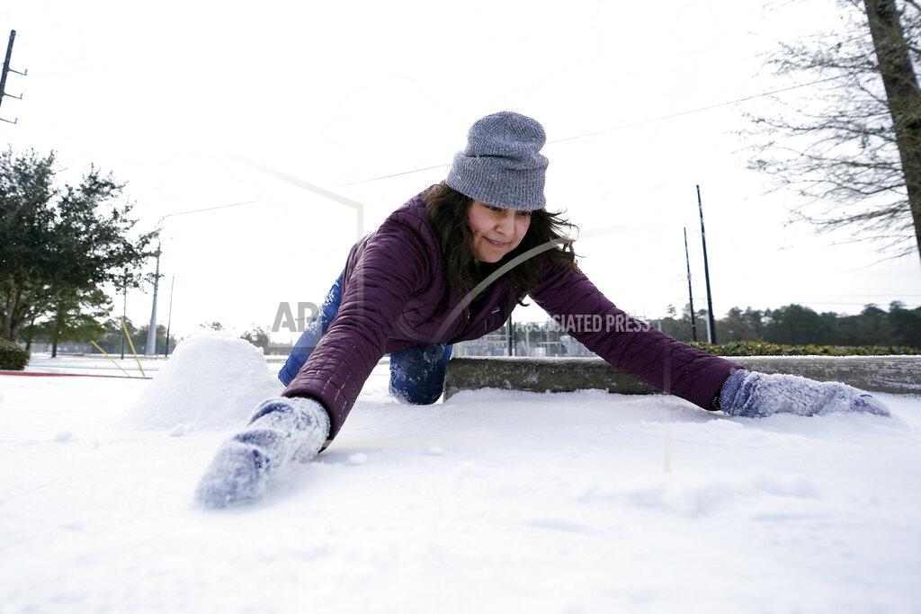 David J. Phillip Cristina Lucero gathers snow while trying to build a snowman Monday, Feb. 15, 2021, in Houston. A winter storm dropping snow and ice sent temperatures plunging across the southern Plains, prompting a power emergency in Texas a day after conditions canceled flights and impacted traffic across large swaths of the U.S. (AP Photo/David J. Phillip)