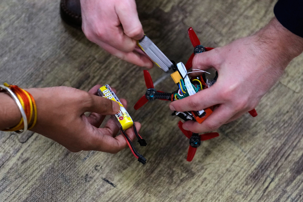 Robotics engineering students change out the battery on a tiny drone at a laboratory at Worcester Polytechnic Institute, Monday, Oct. 20, 2025, in Worcester, Mass. (AP Photo/Charles Krupa)