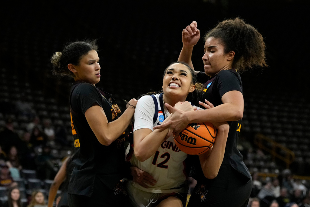 Virginia forward Caitlin Weimar (12) drives to the basket between Arizona State forwards McKinna Brackens, left, and Heloisa Carrera, right, during the second half in a First Four college basketball game in the NCAA Tournament, Thursday, March 19, 2026, in Iowa City, Iowa. (AP Photo/Charlie Neibergall)