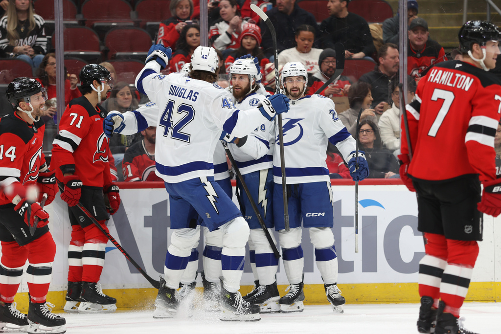 From left, Tampa Bay Lightning's Curtis Douglas (42), Nick Paul (20), Scott Sabourin (46) and Max Crozier (24) react after Paul scored against the New Jersey Devils during the first period of an NHL hockey game Thursday, Dec. 11, 2025, in Newark, N.J. (AP Photo/Pamela Smith)