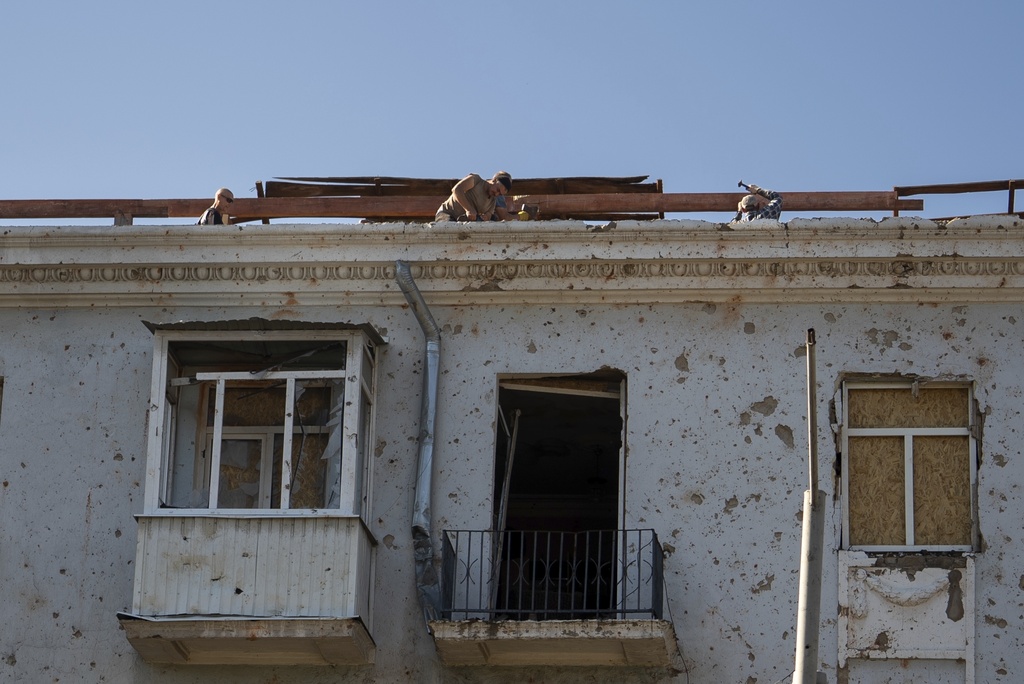 Men repair the roof of a multistory building damaged after a Russian missile hit the city center in Kramatorsk, Donetsk region, Ukraine, Friday, Sept. 12, 2025. (AP Photo/Alex Babenko)