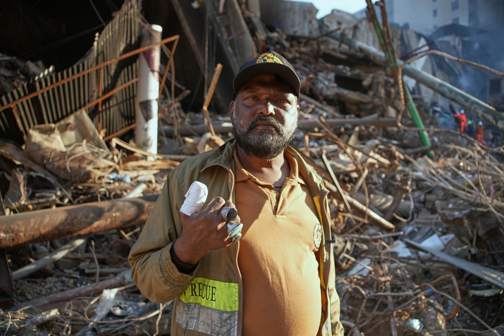 Firefighter Mohammad Aslam, who was injured during rescue operations, stands at the site of a burnt, multi-story shopping plaza in Karachi, Pakistan, Tuesday, Jan. 20, 2026, following a massive fire. (AP Photo/Mohammad Farooq)