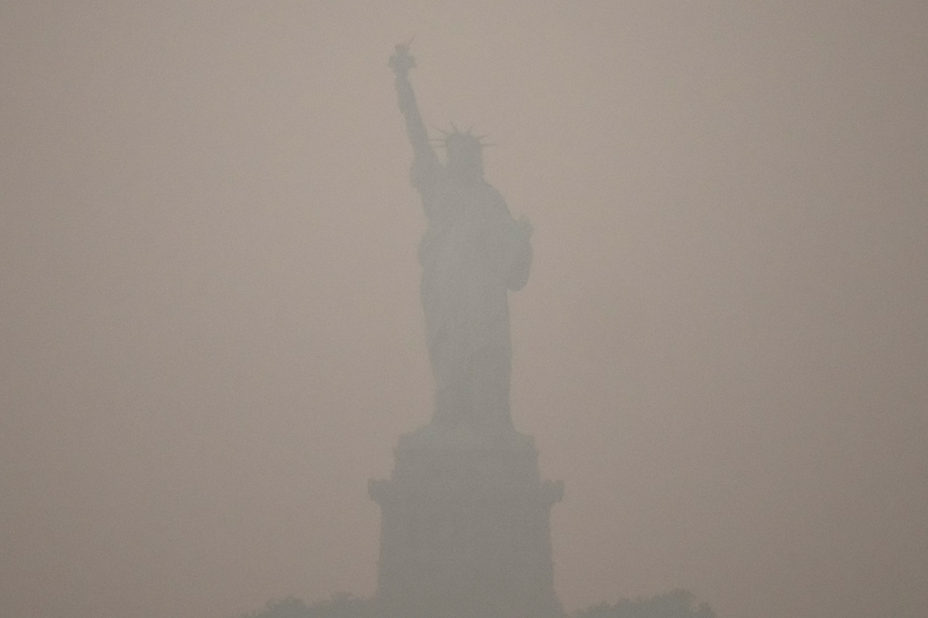 The Statue of Liberty stands during sunset as smoke from wildfires blankets the sky, Thursday, July 16, 2026, in the Brooklyn borough of New York. (AP Photo/Yuki Iwamura)