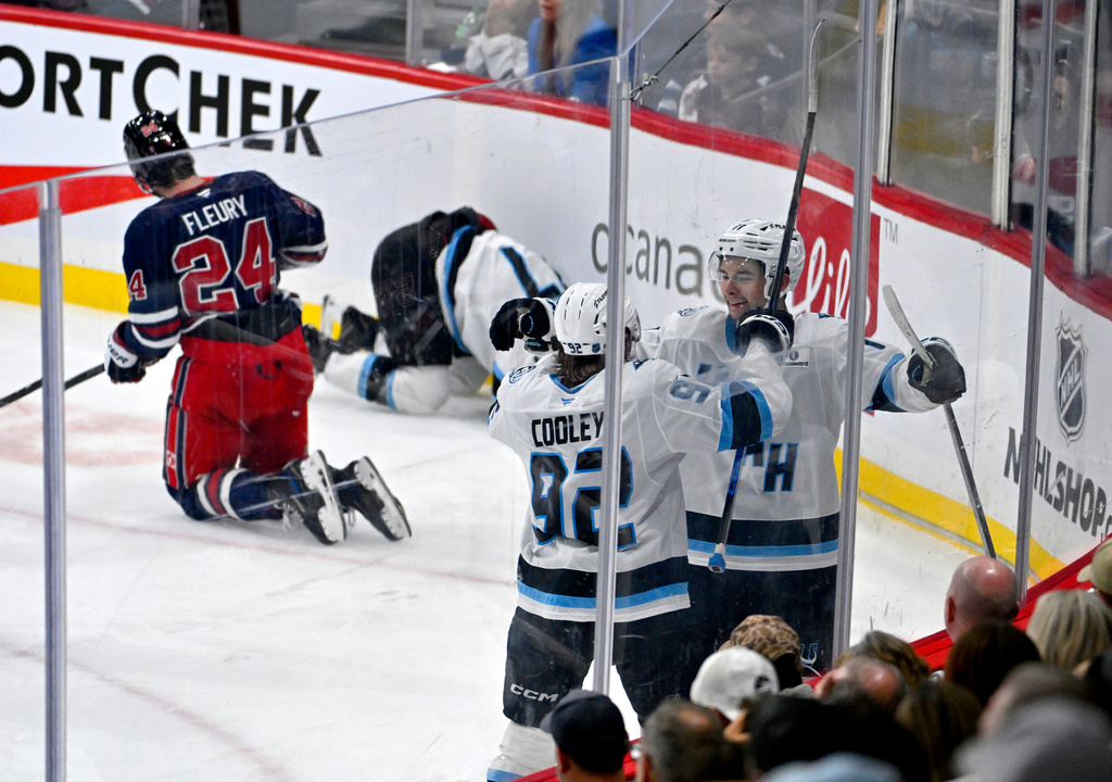 Utah Mammoth's Dylan Guenther (11) celebrates after the winning goal against the Winnipeg Jets with Logan Cooley (92) during the third period of an NHL hockey game in Winnipeg, Manitoba, Sunday, Oct. 26, 2025. (Fred Greenslade/The Canadian Press via AP)