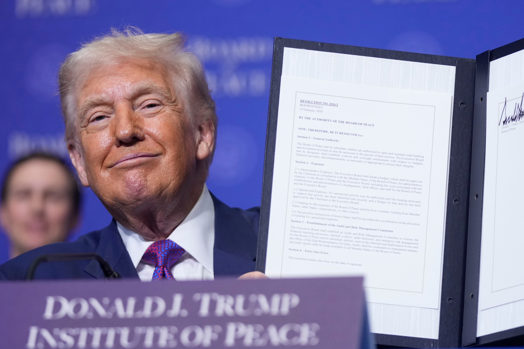 President Donald Trump holds up a signed resolution during a Board of Peace meeting at the U.S. Institute of Peace, Thursday, Feb. 19, 2026, in Washington. (AP Photo/Mark Schiefelbein)