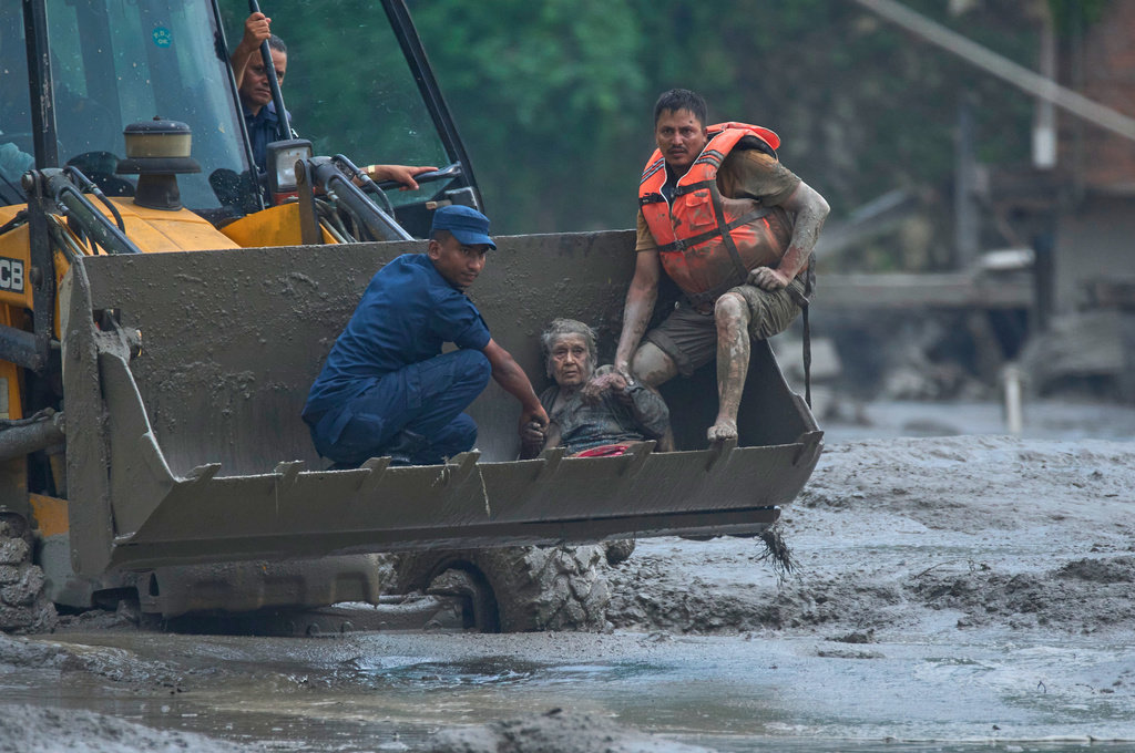 Rescuers use an earthmover to carry a victim of flash flooding to safety along the Trishuli River in Nepal's Nuwakot district, Wednesday, Aug. 26, 2026. (AP Photo/Niranjan Shrestha)