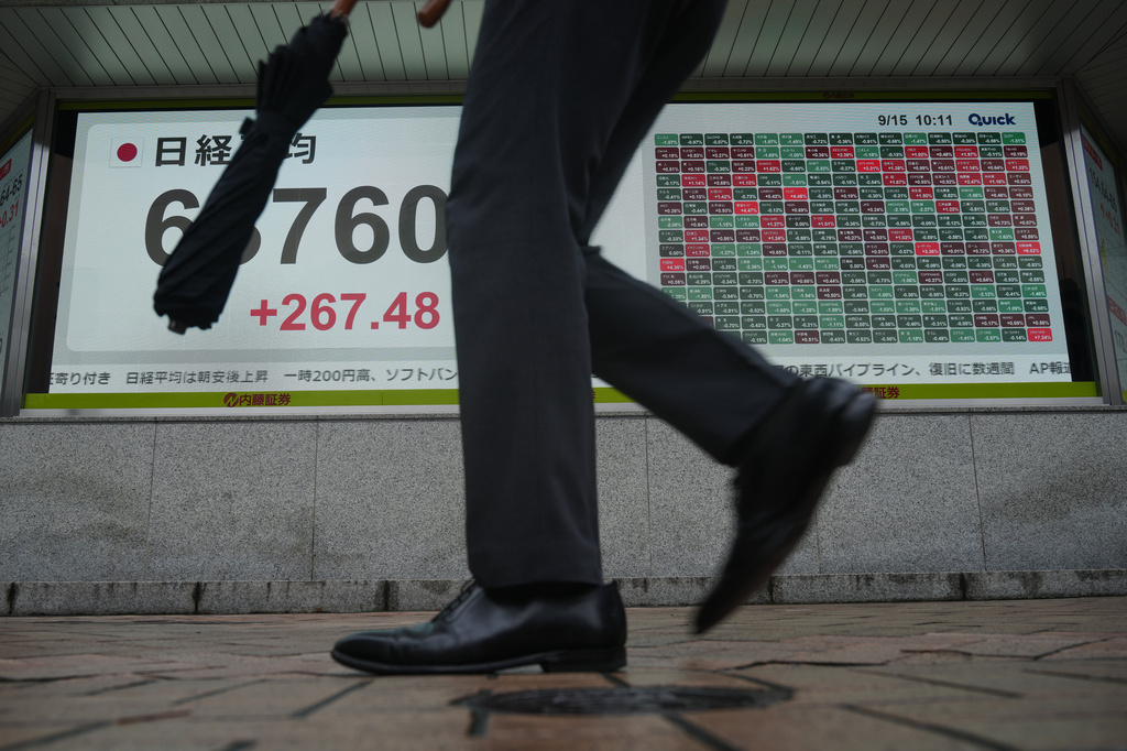 A person walks in front of an electronic stock board showing Japan's Nikkei index at a securities firm Tuesday, Sept. 15, 2026, in Tokyo. (AP Photo/Eugene Hoshiko)