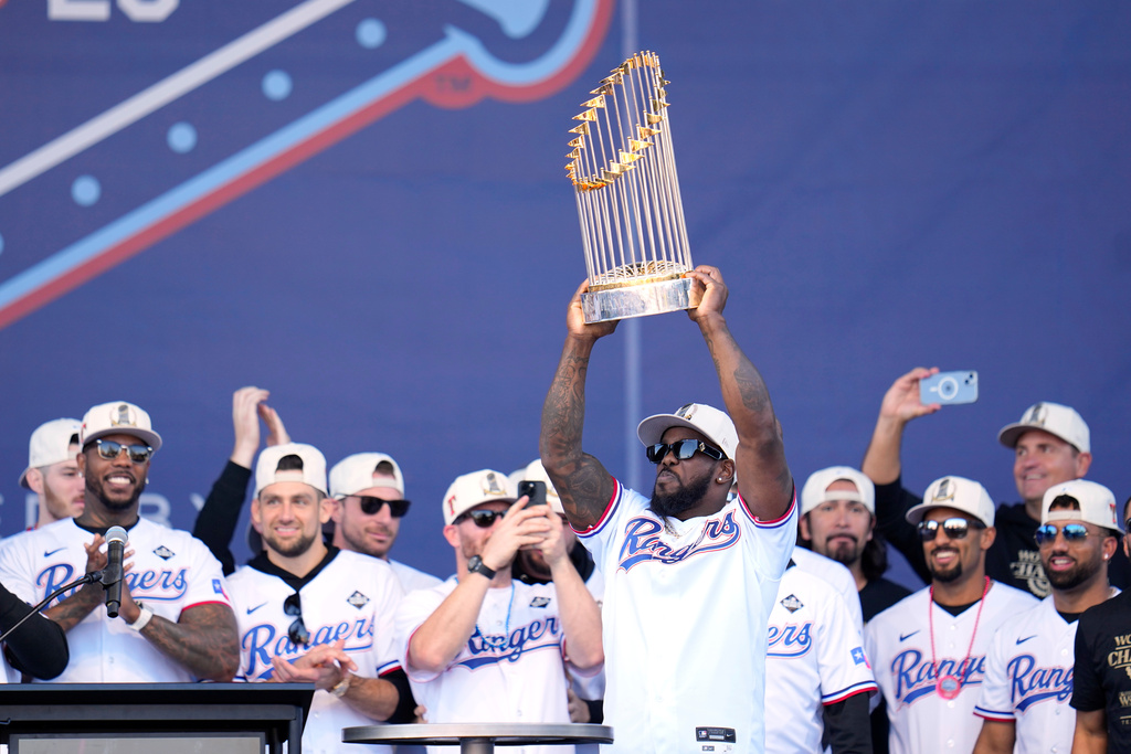 FILE - Texas Rangers' Adolis Garcia, surrounded by teammates and staff, holds up the Commissioner's Trophy during a World Series baseball championship celebration, Friday, Nov. 3, 2023, in Arlington, Texas. (AP Photo/Julio Cortez, File)