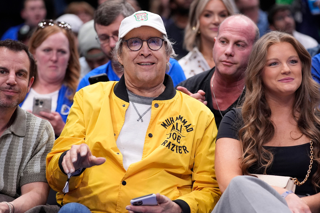 FILE - Actor Chevy Chase, center, sits on the front row during the second half of an NBA basketball game between the Atlanta Hawks and Dallas Mavericks in Dallas on April 4, 2024. (AP Photo/LM Otero, File)