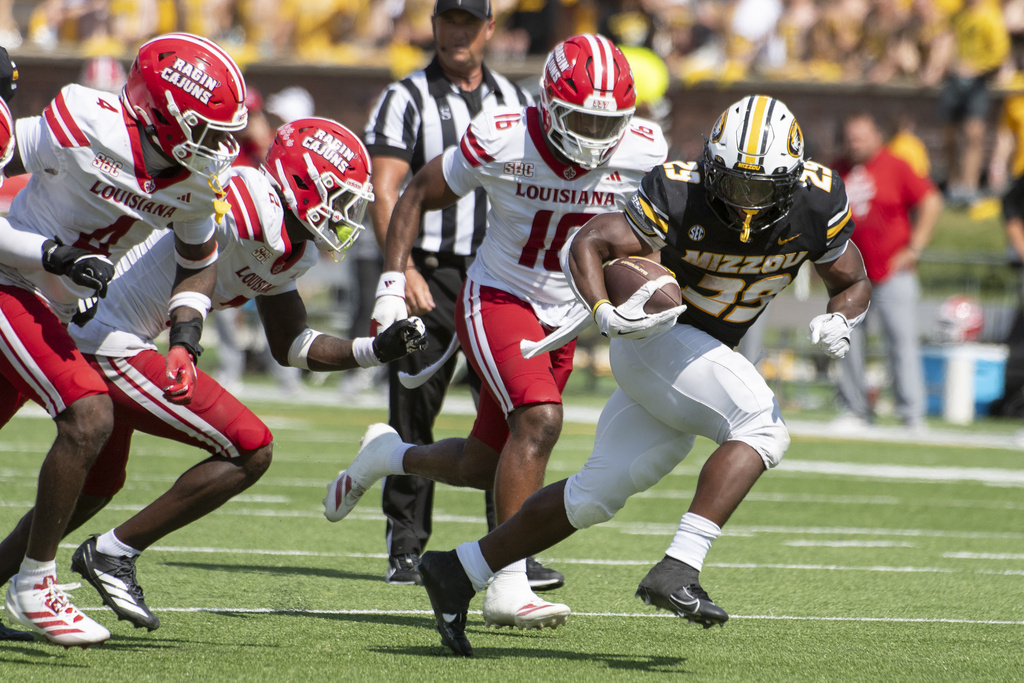 Missouri running back Ahmad Hardy, right, runs past Louisiana-Lafayette linebacker Kailep Edwards (16), Tyree Skipper (4) and Jalen Clark (2) during the second half of an NCAA college football game Saturday, Sept. 13, 2025, in Columbia, Mo. (AP Photo/L.G. Patterson)