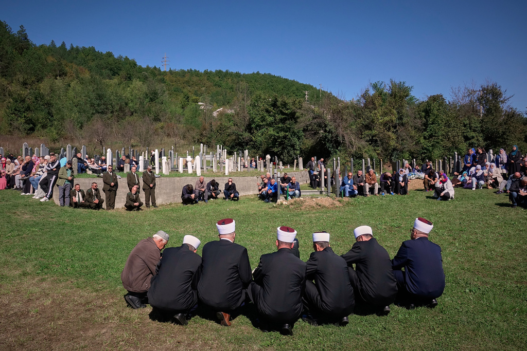 People pray during a memorial service, a year after floods and a landslide swept through the tiny village of Donja Jablanica in southern Bosnia, killing 19 people, Saturday, Oct. 4, 2025. (AP Photo/Eldar Emric)