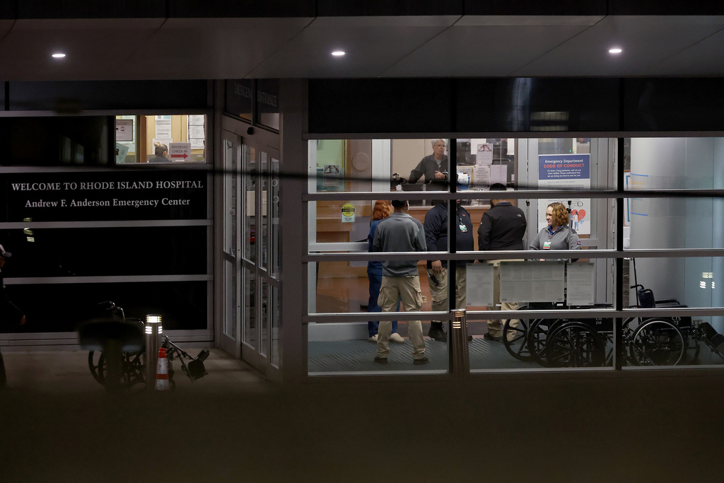 People stand at an entrance to Rhode Island Hospital in Providence, R.I., on Saturday, Dec. 13, 2025, where victims from a shooting at Brown University were transported. (AP Photo/Mark Stockwell)