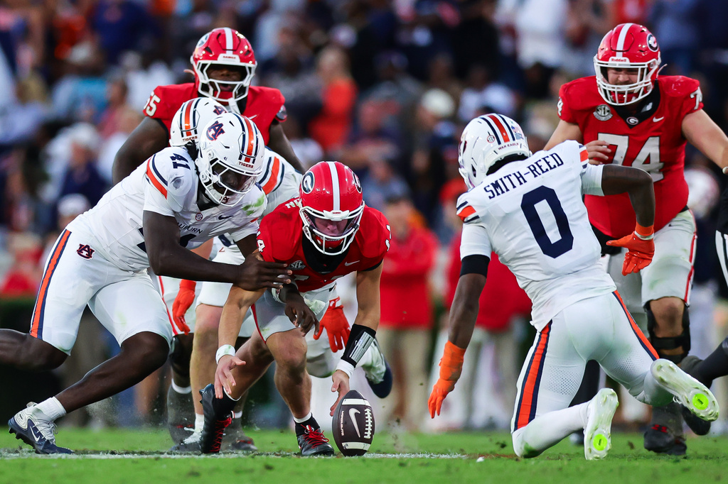 Georgia quarterback Gunner Stockton, center, fumbles as Auburn defensive end Jared Smith, left, and defensive back Sylvester Smith-Reed (0) close in during the second half of an NCAA college football game, Saturday, Oct. 17, 2026, in Athens, Ga. (AP Photo/Colin Hubbard)