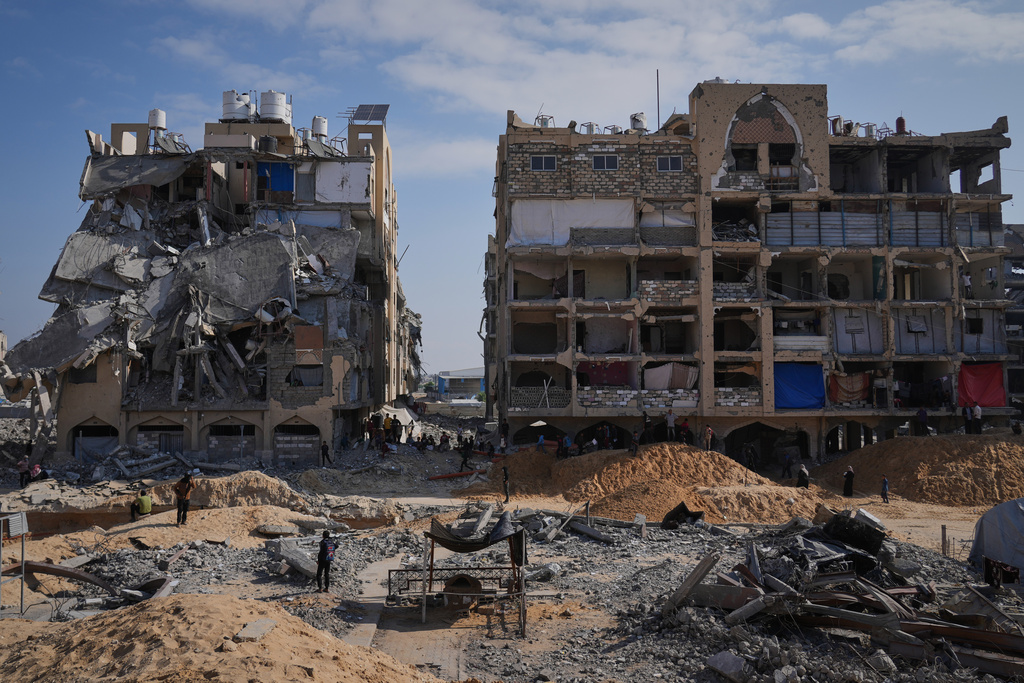 Members of the Hamas militant group search underground for the bodies of Israeli hostages amid destroyed buildings in Khan Younis, in the southern Gaza Strip, Sunday, Oct. 19, 2025. (AP Photo/Abdel Kareem Hana)