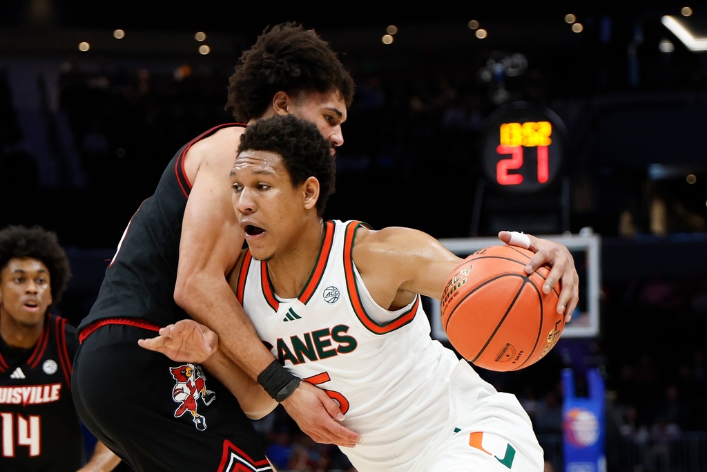 Miami forward Malik Reneau (5) drives against Louisville guard J'vonne Hadley during the first half of an NCAA college basketball game in the quarterfinals of the Atlantic Coast Conference tournament in Charlotte, N.C., Thursday, March 12, 2026. (AP Photo/Nell Redmond)
