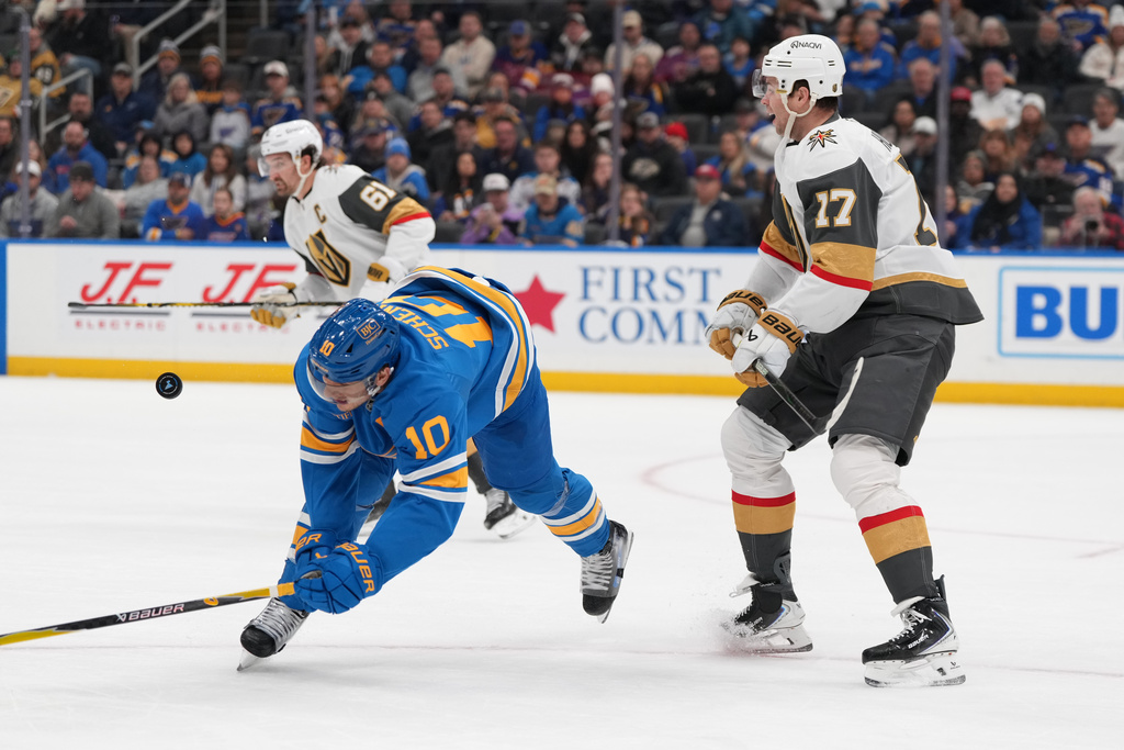St. Louis Blues' Brayden Schenn (10) and Vegas Golden Knights' Ben Hutton (17) battle for a loose puck during the second period of an NHL hockey game Friday, Jan. 2, 2026, in St. Louis. (AP Photo/Jeff Roberson)