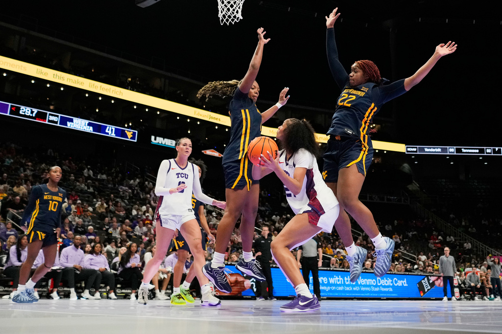 TCU guard Taliyah Parker, front center, looks to shoot under pressure from West Virginia forwards Carter McCray, center, and Kierra Wheeler (22) during second half of the NCAA college basketball championship game at the Big 12 Conference tournament Sunday, March 8, 2026, in Kansas City, Mo. (AP Photo/Charlie Riedel)
