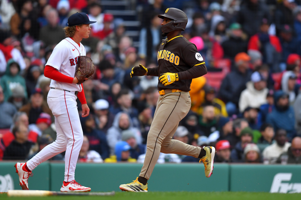 San Diego Padres' Miguel Andujar, right, runs toward home past Boston Red Sox pitcher Connelly Early, left, to score on a one-run double by Freddy Fermin in the third inning of a baseball game, Saturday, April 4, 2026, in Boston. (AP Photo/Steven Senne)