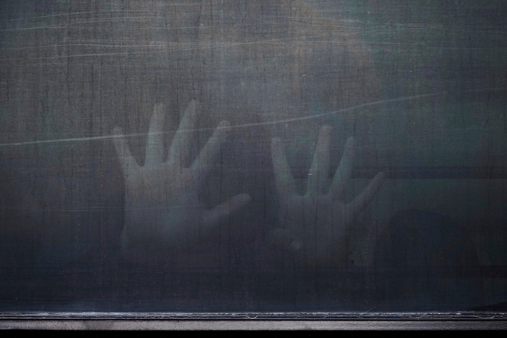 A woman from Peru signals through the barred and tinted windows of a bus after she was detained following an appearance at immigration court, June 23, 2025, in San Antonio. (AP Photo/Eric Gay, File)