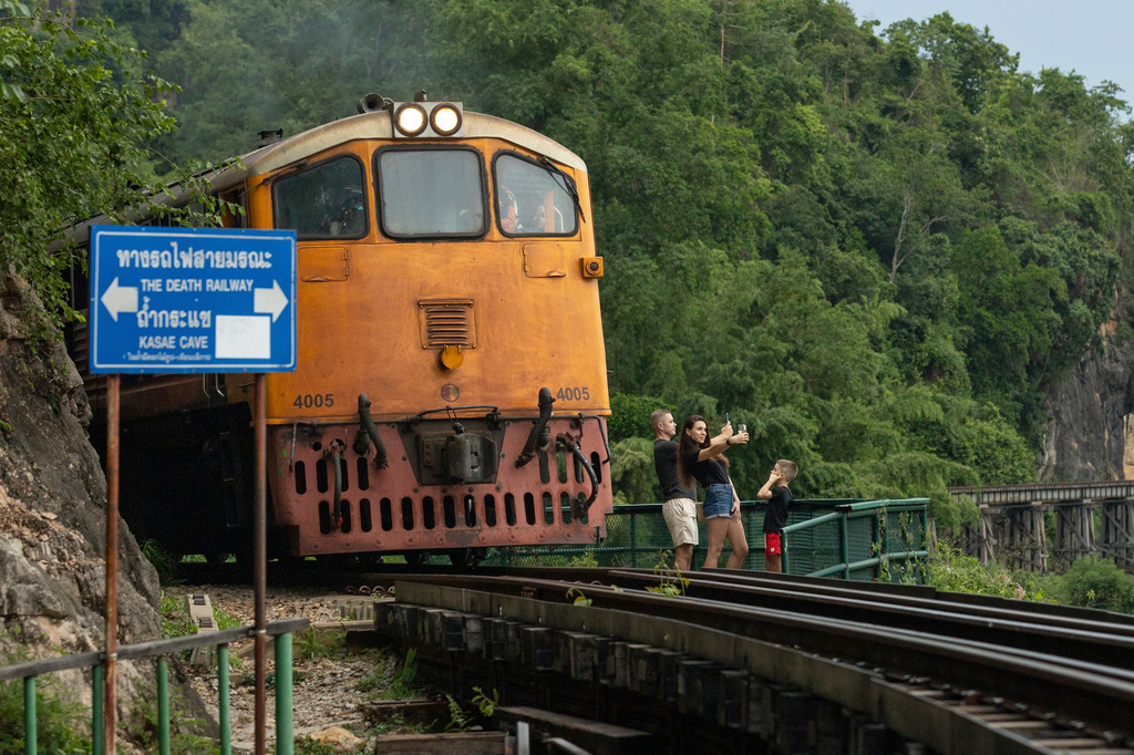 A family of Russian tourists pose for photos as a train approaches Thamkra Sae Station, one of the still active sections of the infamous World War II "Death Railway," in Sai Yok, Thailand, Thursday, May 28, 2026. (AP Photo/Anton L. Delgado)