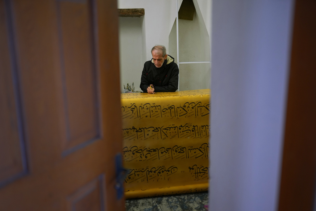 Iraqi calligrapher Ali Zaman works in one scroll of a massive handwritten manuscript of the Quran, Islam's holy book, at the Mihrimah sultan mosque, in Istanbul, Turkey, Wednesday, Jan. 14, 2026. (AP Photo/Francisco Seco)