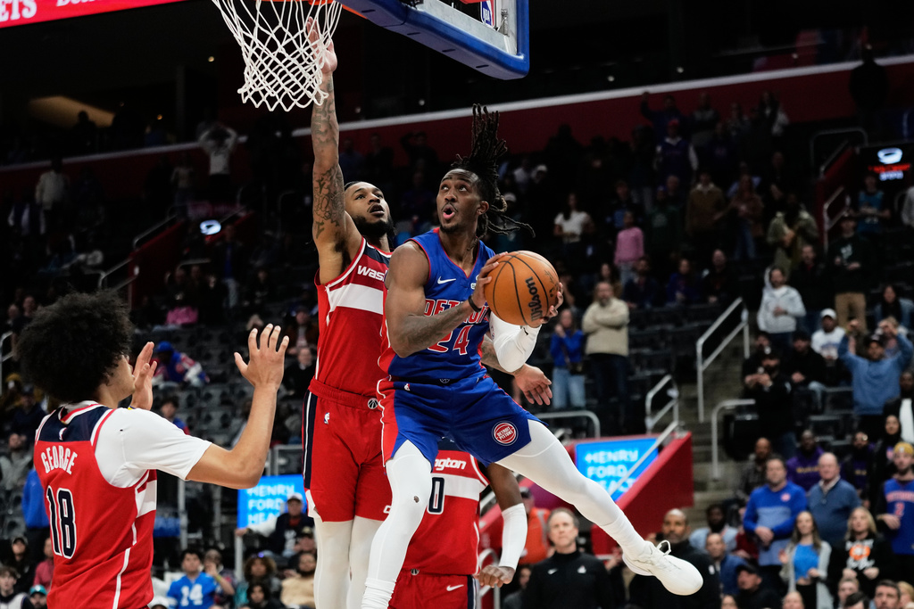 Detroit Pistons guard Daniss Jenkins, right, shoots against Washington Wizards forward Kyshawn George, left, and forward Cam Whitmore during overtime in an NBA basketball game Monday, Nov. 10, 2025, in Detroit. (AP Photo/Ryan Sun)