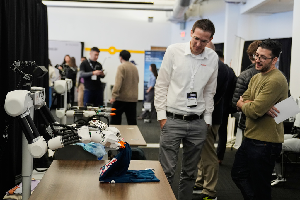 People watch as a robot, made by Weave Robotics, folds clothes during the Humanoids Summit, Thursday, Dec. 11, 2025, in Mountain View, Calif. (AP Photo/Godofredo A. Vásquez)