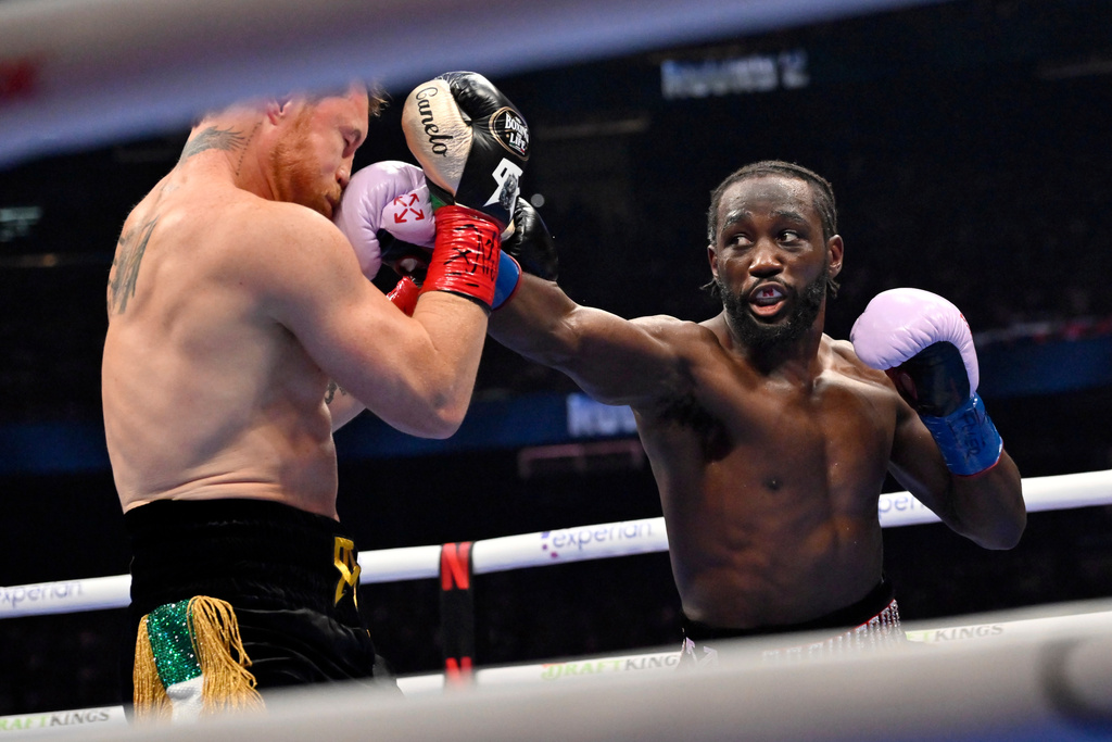 FILE - Terence Crawford, right, connects with Canelo Alvarez during a super middleweight championship boxing match in Las Vegas, Sept. 13, 2025. (AP Photo/David Becker, File)