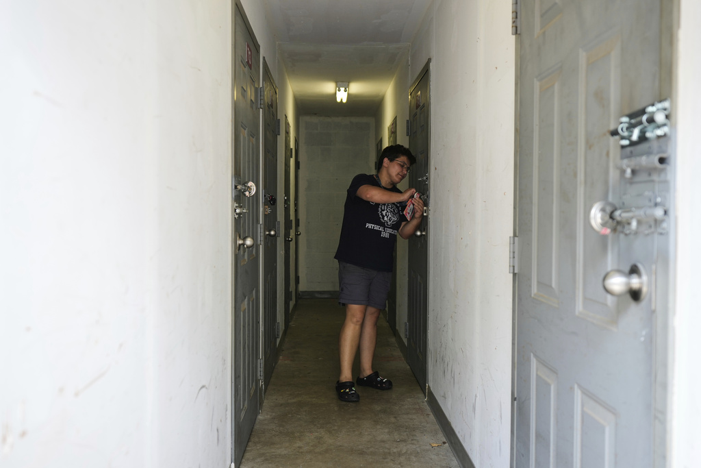 Liz Silva locks the door to a storage unit containing her friend Maria Pires' belongings in Baltimore, Wednesday, June 25, 2025. (AP Photo/Stephanie Scarbrough)