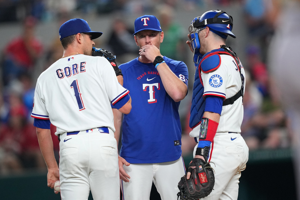 Texas Rangers starting pitcher MacKenzie Gore (1) has a conference with pitching coach Jordan Tiegs, center, and catcher Danny Jansen during the third inning of a baseball game against the Athletics, Saturday, April 25, 2026, in Arlington, Texas. (AP Photo/Julio Cortez)