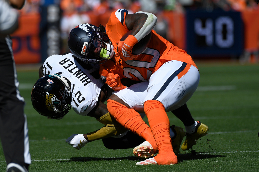 Denver Broncos running back Jonah Coleman (20) is hit by Jacksonville Jaguars cornerback Travis Hunter (12) after Coleman caught a pass in the first half of an NFL football game in Denver, Sunday, Sept. 20, 2026. (AP Photo/Eric Lutzens)