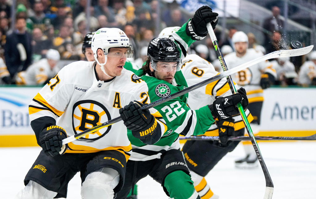 Boston Bruins defenseman Hampus Lindholm (27) and Dallas Stars center Mavrik Bourque (22) compete for the puck during the first period of an NHL hockey game, Tuesday, Jan. 20, 2026, in Dallas. (AP Photo/Jeffrey McWhorter)