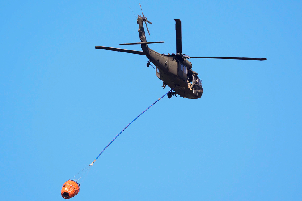 A helicopter carries water to the Brantley Highway 82 fire, Thursday, April 23, 2026, near Nahunta, Ga. (AP Photo/Mike Stewart)