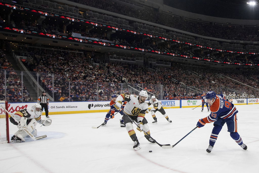 Vegas Golden Knights' Shea Theodore (27) and Edmonton Oilers' Ryan Nugent-Hopkins (93) battle for the puck as Golden Knight's goalie Carter Hart (79) defends during the second period of an NHL hockey game in Edmonton, Alberta, on Saturday April 4, 2026. (Jason Franson/The Canadian Press via AP)